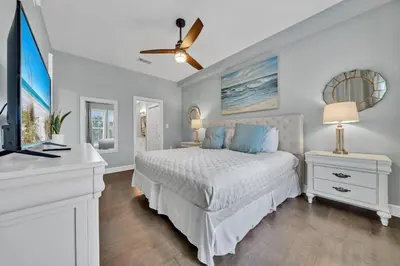 a white bedroom with a bed and a tv at Stunning Village Condo, Overlooking 30A, Beautifully Decorated Recently Updated in Rosemary Beach