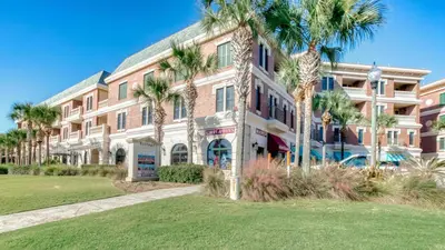 a large building with palm trees in front of it at Stunning Village Condo, Overlooking 30A, Beautifully Decorated Recently Updated in Rosemary Beach