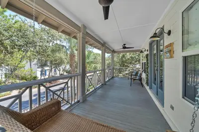 a screened porch with chairs on a house at Pelicans Nest II - Easy walk to the beach & Pool in Santa Rosa Beach