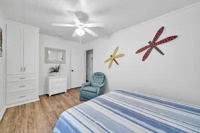 a bedroom with a bed and a blue chair at Pelicans Nest II - Easy walk to the beach & Pool in Santa Rosa Beach