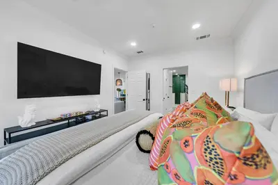 a white bedroom with a large flat screen tv on the wall at Newly Renovated Professionally Decorated Gulf Views! Pool & Beach Access in Rosemary Beach