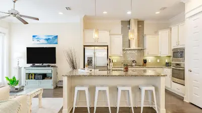 a kitchen with a large island with bar stools at Emerald Gem by AvantStay Pool Access 3mins to Beach in Panama City Beach