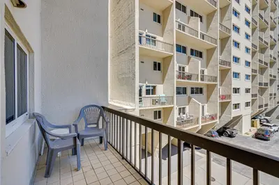 a balcony with a blue chair and a building at Beachfront Panama City Condo with Balcony and Views! in Panama City