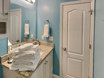 a bathroom with blue walls and a sink with white towels at Horizon South #31A in Panama City Beach