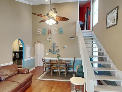 a living room with a staircase leading to a dining room at Horizon South #31A in Panama City Beach