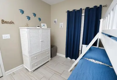 a bedroom with a bunk bed and blue curtains at Beachfront Oasis at Splash Resort and Condos in Panama City Beach