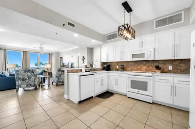 a kitchen with white cabinets and a living room at Gulf Crest 205 - Stunning Gulf Views - Huge Balcony in Panama City Beach