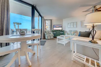 a living room with a table and a living room with a view at Sunbird Resort! Ground-Floor Renovated Beach Condo! Free Beach Chairs! by Dolce Vita Getaways PCB in Panama City Beach