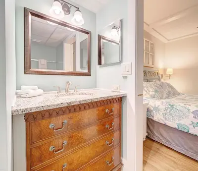 a bathroom with a sink and a bedroom with a bed at Sunbird Resort! Ground-Floor Renovated Beach Condo! Free Beach Chairs! by Dolce Vita Getaways PCB in Panama City Beach