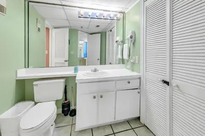 a bathroom with a toilet and a sink and a mirror at Sunbird 906W in Panama City Beach