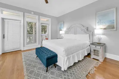 a white bedroom with a bed and a blue stool at Lily Pad in Panama City Beach