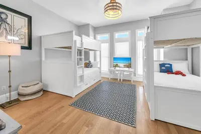 a bedroom with white bunk beds and a blue rug at Lily Pad in Panama City Beach