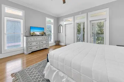 a white bedroom with a large bed and a flat screen tv at Lily Pad in Panama City Beach