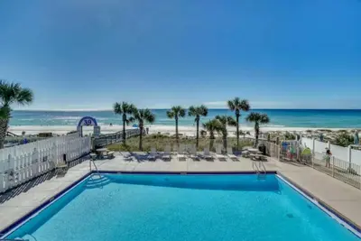 a pool with the beach in the background at The Original Robin's Nest/ 5 Min Walk To The Beach in Panama City Beach