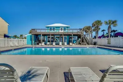 a swimming pool with chairs and a house at The Original Robin's Nest/ 5 Min Walk To The Beach in Panama City Beach