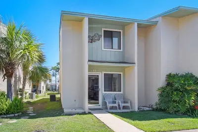 a white house with two chairs in the front yard at The Original Robin's Nest/ 5 Min Walk To The Beach in Panama City Beach