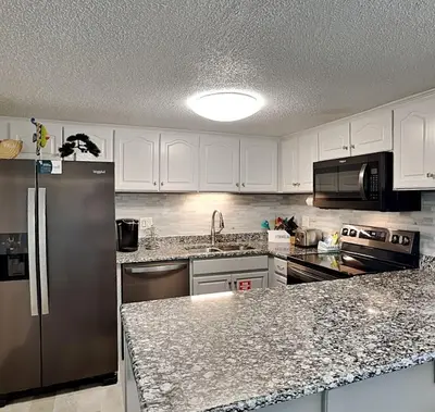 a kitchen with white cabinets and a stainless steel refrigerator at Pinnacle Port a-702 in Panama City Beach