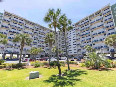 a large apartment building with palm trees in a park at Pinnacle Port a-702 in Panama City Beach