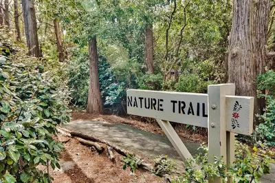 a sign for a nature trail in the woods at Cassine Gardens by Panhandle Getaways in Santa Rosa Beach