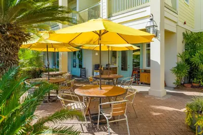 a group of tables and chairs with yellow umbrellas at Cassine Gardens by Panhandle Getaways in Santa Rosa Beach