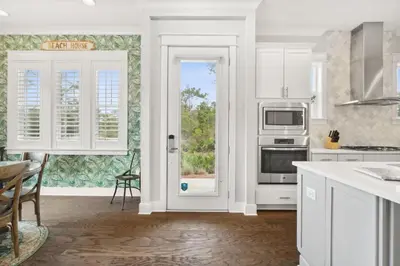 a kitchen with white cabinets and a door with a window at Coastal Cottage at 30A in Inlet Beach