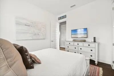 a white bedroom with a bed and a dresser at Coastal Cottage at 30A in Inlet Beach