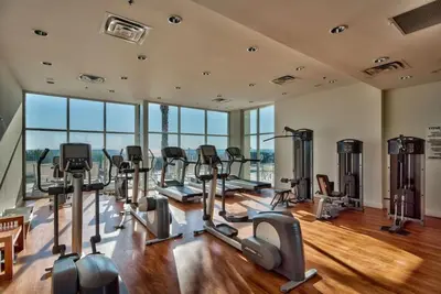 a gym with treadmills and ellipticals in a room with windows at Sterling Breeze 1507 in Panama City Beach