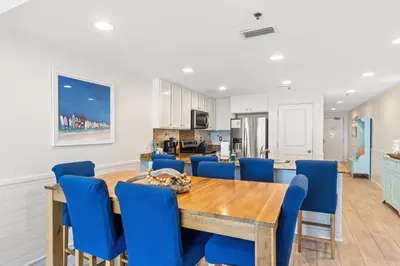 a dining room with a wooden table and blue chairs at Sterling Breeze 1507 in Panama City Beach