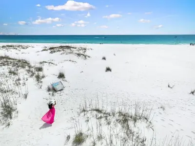 a woman in a pink dress walking on a beach at Gulf-Front Shores of Panama Condo w/ Balcony & Resort Amenities in Panama City Beach