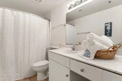 a bathroom with a sink and a toilet and a mirror at Gulf-Front Shores of Panama Condo w/ Balcony & Resort Amenities in Panama City Beach