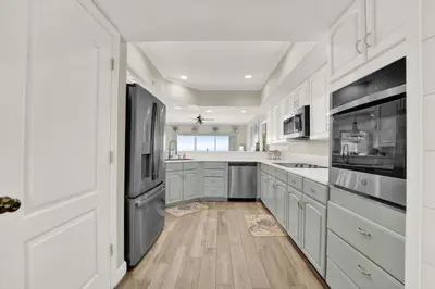 a kitchen with white cabinets and stainless steel appliances at Coral Reef 1001 in Panama City Beach
