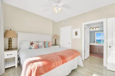 a white bedroom with a bed and a bathroom at Family-Friendly 4BR Beachfront Retreat w/ Indoor & Outdoor Pools in Panama City Beach