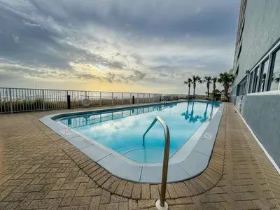 a large swimming pool with the ocean in the background at Family-Friendly 4BR Beachfront Retreat w/ Indoor & Outdoor Pools in Panama City Beach
