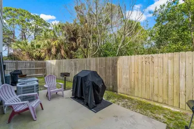 a backyard with two chairs and a grill and a fence at Emerald Coast Villa in Panama City Beach