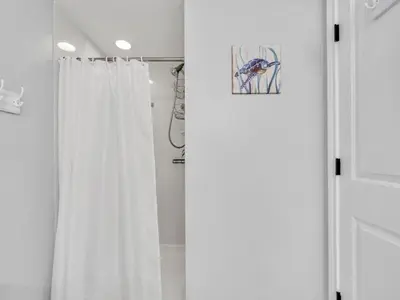 a bathroom with a shower with a white shower curtain at Shores of Panama 1002 in Panama City Beach