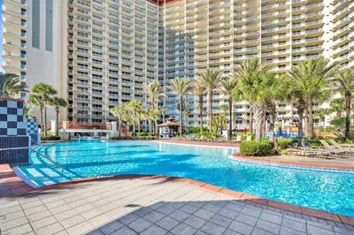 a swimming pool with palm trees and a large building at Shores of Panama 1002 in Panama City Beach