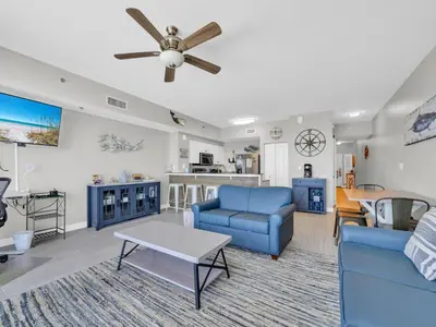 a living room with blue furniture and a ceiling fan at Shores of Panama 1002 in Panama City Beach
