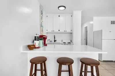 a kitchen with a white counter and two bar stools at Top of the Gulf 421 - Luxury Beach View Condo in Panama City Beach