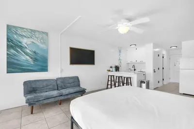 a bedroom with a bed and a chair and a kitchen at Top of the Gulf 421 - Luxury Beach View Condo in Panama City Beach