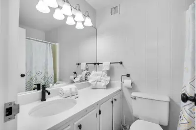 a bathroom with a sink and a toilet and a mirror at Top of the Gulf 421 - Luxury Beach View Condo in Panama City Beach
