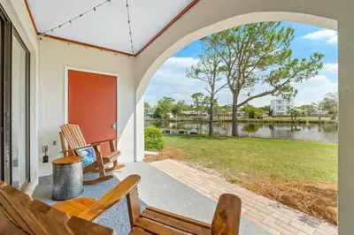 a porch with chairs and a view of a lake at The Beachy Boater at St Thomas Square #305 by Nautical Properties in Panama City Beach