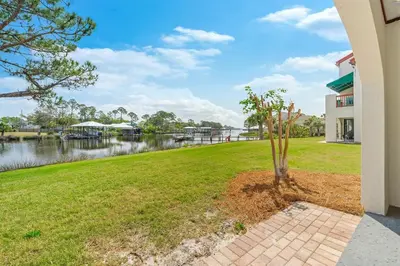a tree in the grass next to a building at The Beachy Boater at St Thomas Square #305 by Nautical Properties in Panama City Beach