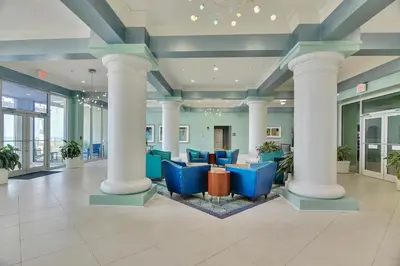 a lobby with blue chairs and columns in a building at Boardwalk Beach Resort #1400 by Book That Condo in Panama City Beach