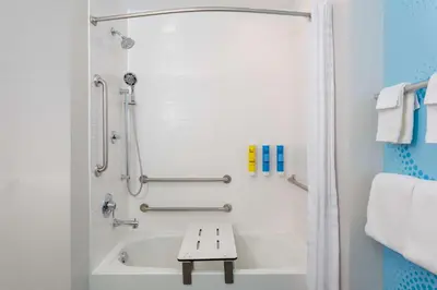 a bathroom with a tub and a bench in it at Tru By Hilton Panama City Beach in Panama City Beach