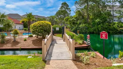 a walkway over a pond in a yard with a fence at St Thomas Square 1208A in Panama City Beach