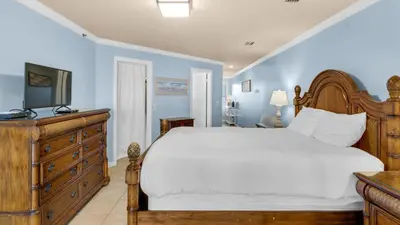 a bedroom with a bed and a dresser with a television at St Thomas Square 1208A in Panama City Beach