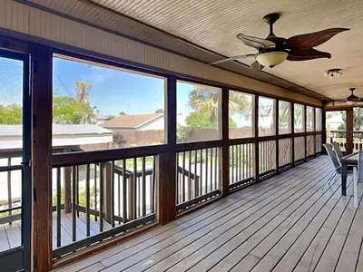 a screened porch with a ceiling fan and windows at Gulf Six in Panama City Beach