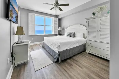 a bedroom with a bed and a dresser and a window at Aqua Resort 903 in Panama City Beach