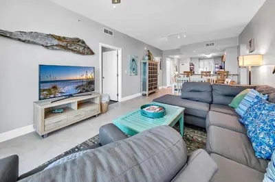 a living room with a couch and a tv at Aqua Resort 903 in Panama City Beach