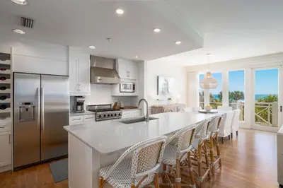 a kitchen with a large white island with chairs at Gulf Front - Large Pool - Bikes - Gated Community in Inlet Beach